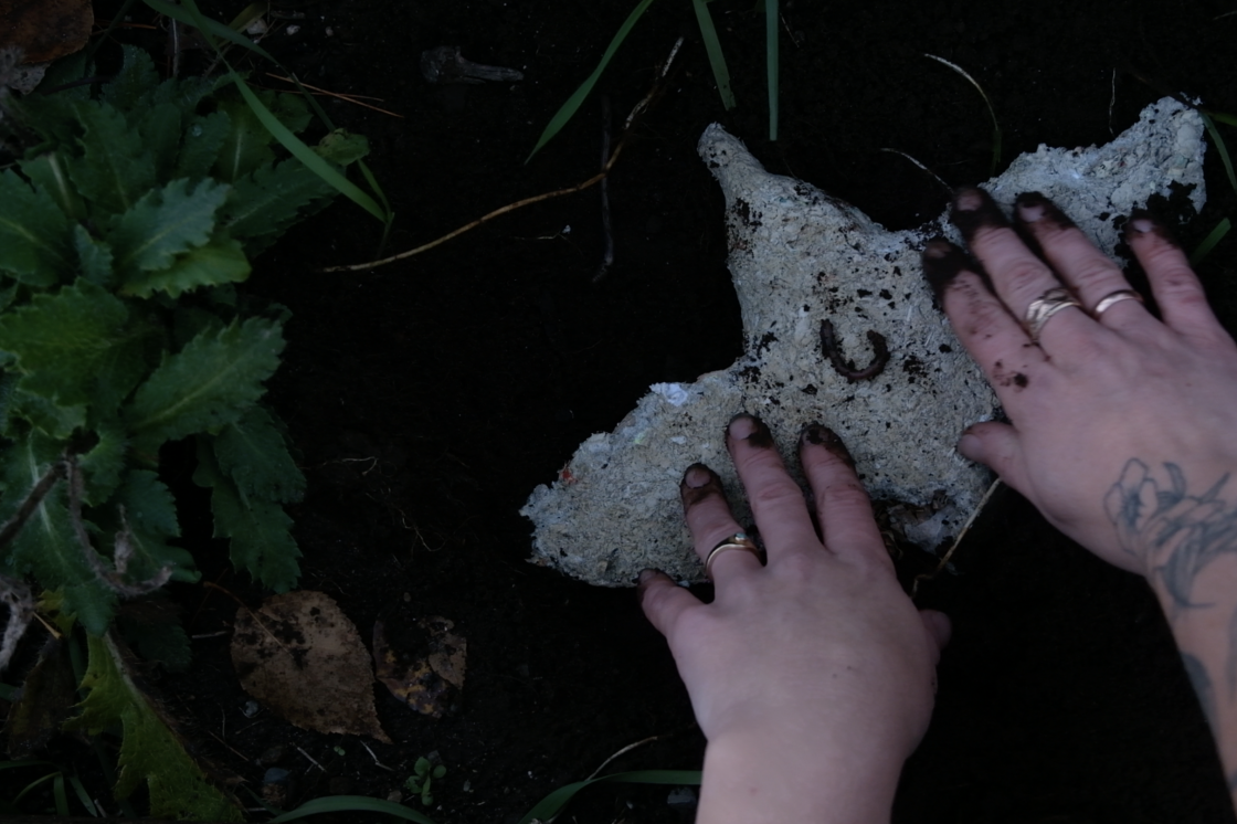 One of Abby's paper-pulp, seed-infused pieces being planted in the soil.