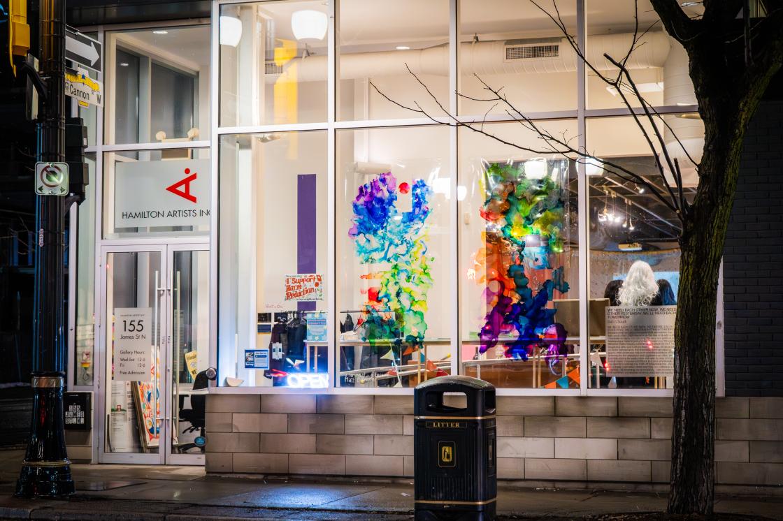 A photo from outside of our James Street windows at nighttime, featuring Matt Dampier's 'a remnant, a record' diptych on the windows. 