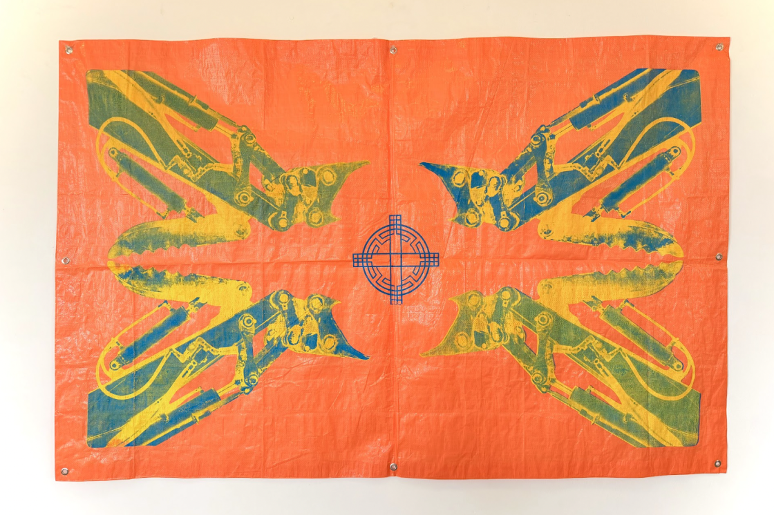 A neon orange tarp that has prints in each corner in shades of yellow, green and blue. There is a blue, rounded symbol in the middle.