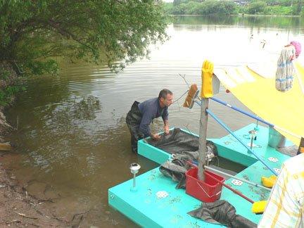 Man launching a bright blue boat in the lake.