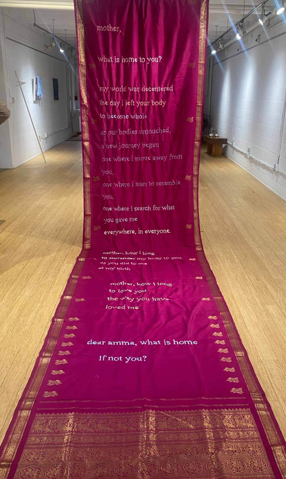 A long hot pink saree with decorative gold details and a long hand embroidered poem by Par Nair