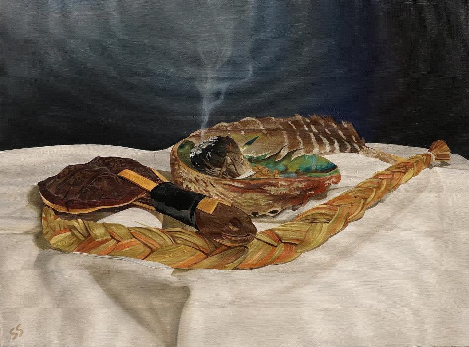 The image is a photo of an oil painting. The painting features a table with several traditional Haudenosaunee spiritual objects. A turtle rattle, a braid of sweet grass, a seashell with burning white sage inside. Along the rim of the seashell, a feather rests. All the items rest on an off-white table cloth against a dark blue backdrop. Smoke rises from the bundle of white sage in the center of the seashell. The painting is called "Just Spiritual Things: A N8V Still Life".