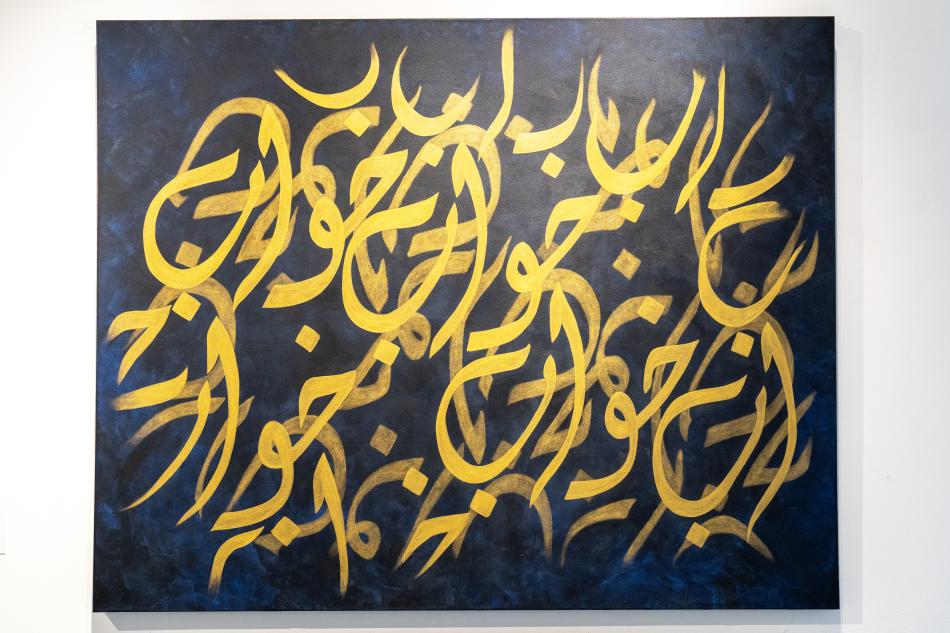 One of Rania's works, featuring layers of bright yellow arabic symbols, arranged in a flowing, natural way - some symbols are faded into the background. The base background of the painting is a deep, rich, dark blue. 